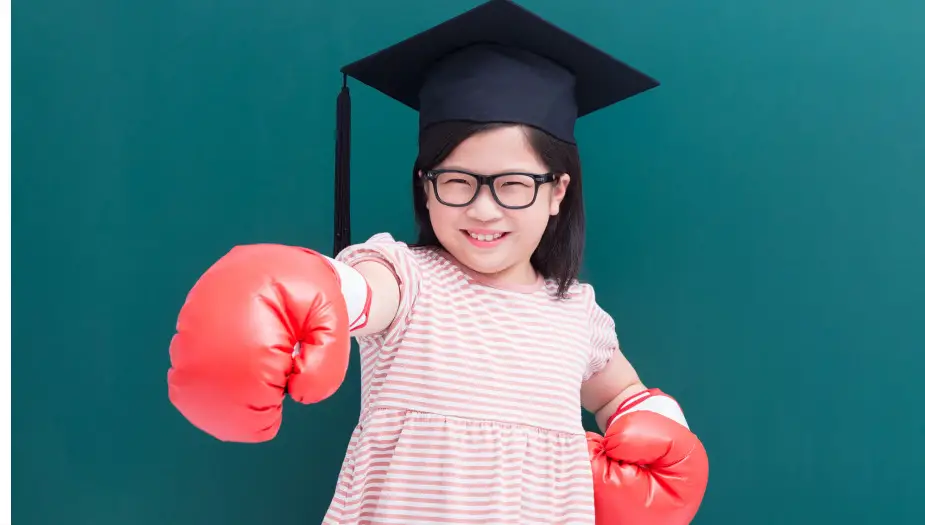 Young student wearing boxing gloves smiling about her academic strengths